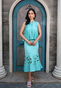 Model wearing a pastel aqua pleated sleeveless top with a matching embroidered midi skirt from Arcadian Dream SS’26.
