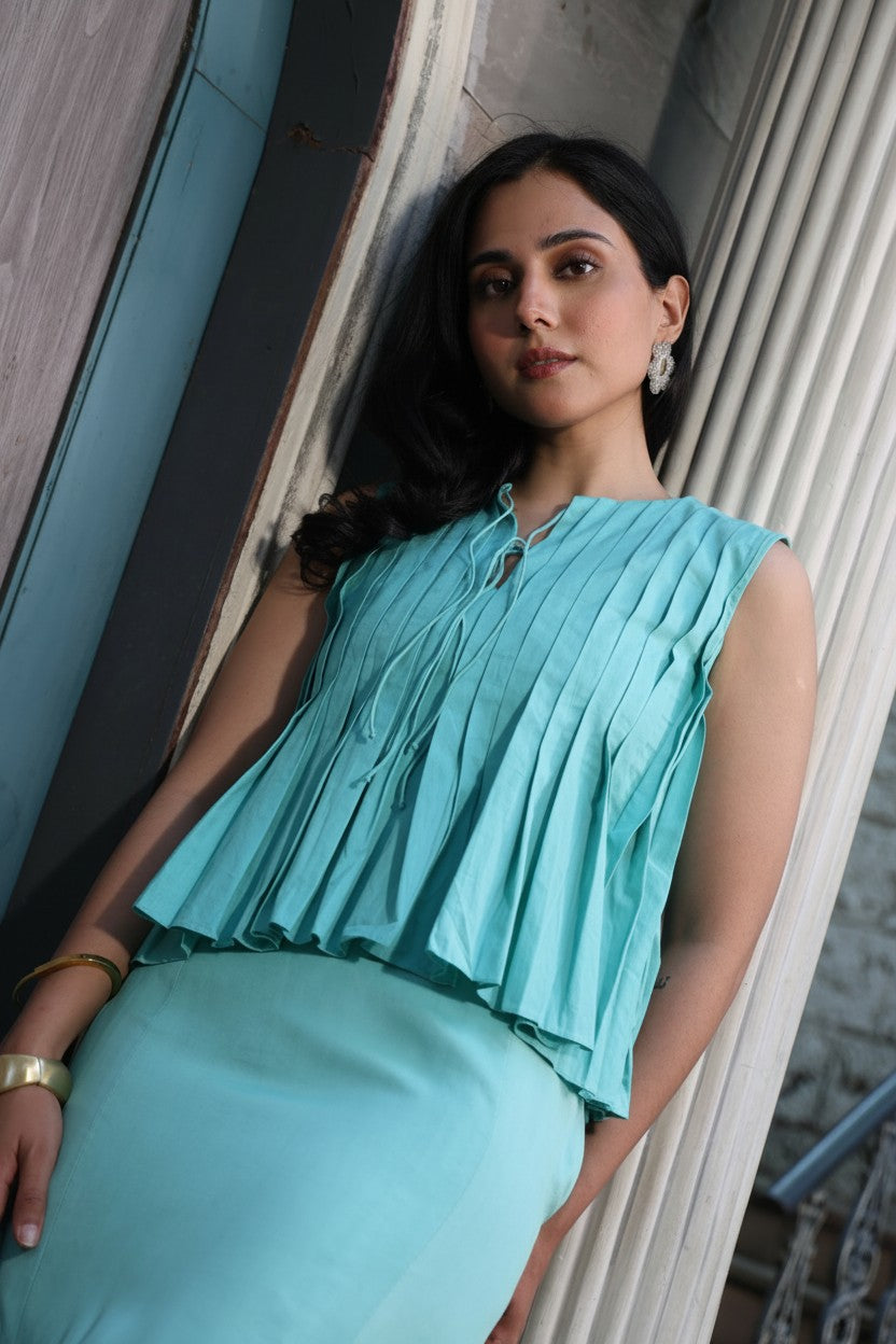 Modern top in aqua blue with airy pleated detailing and statement top.