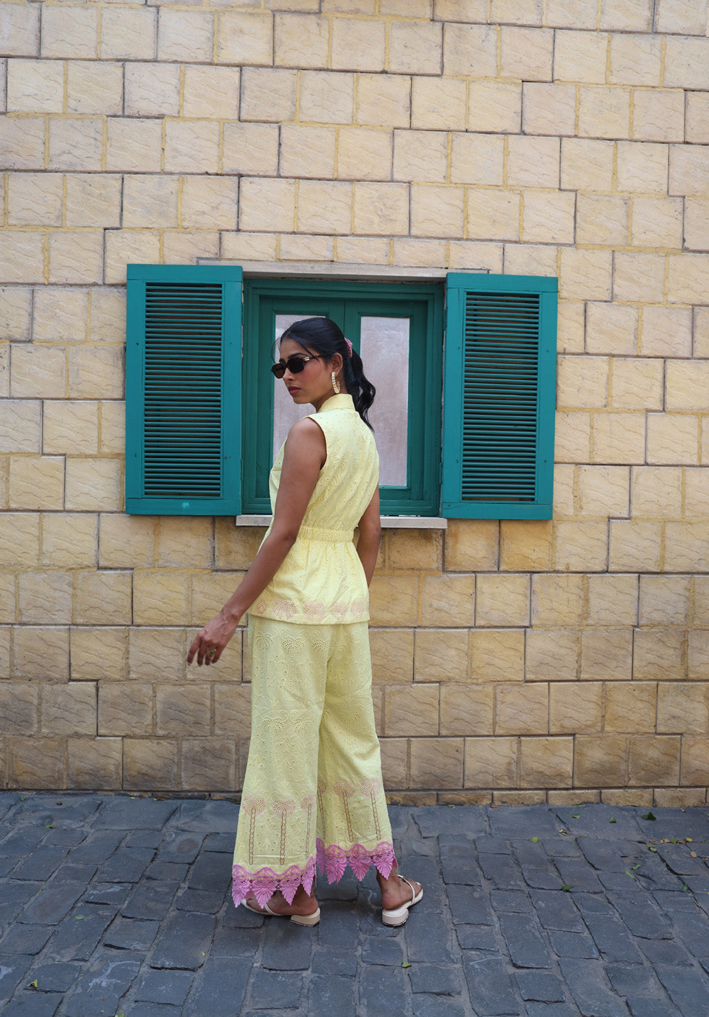Side view of pastel yellow coord set with palm embroidery and pink lace hem detailing