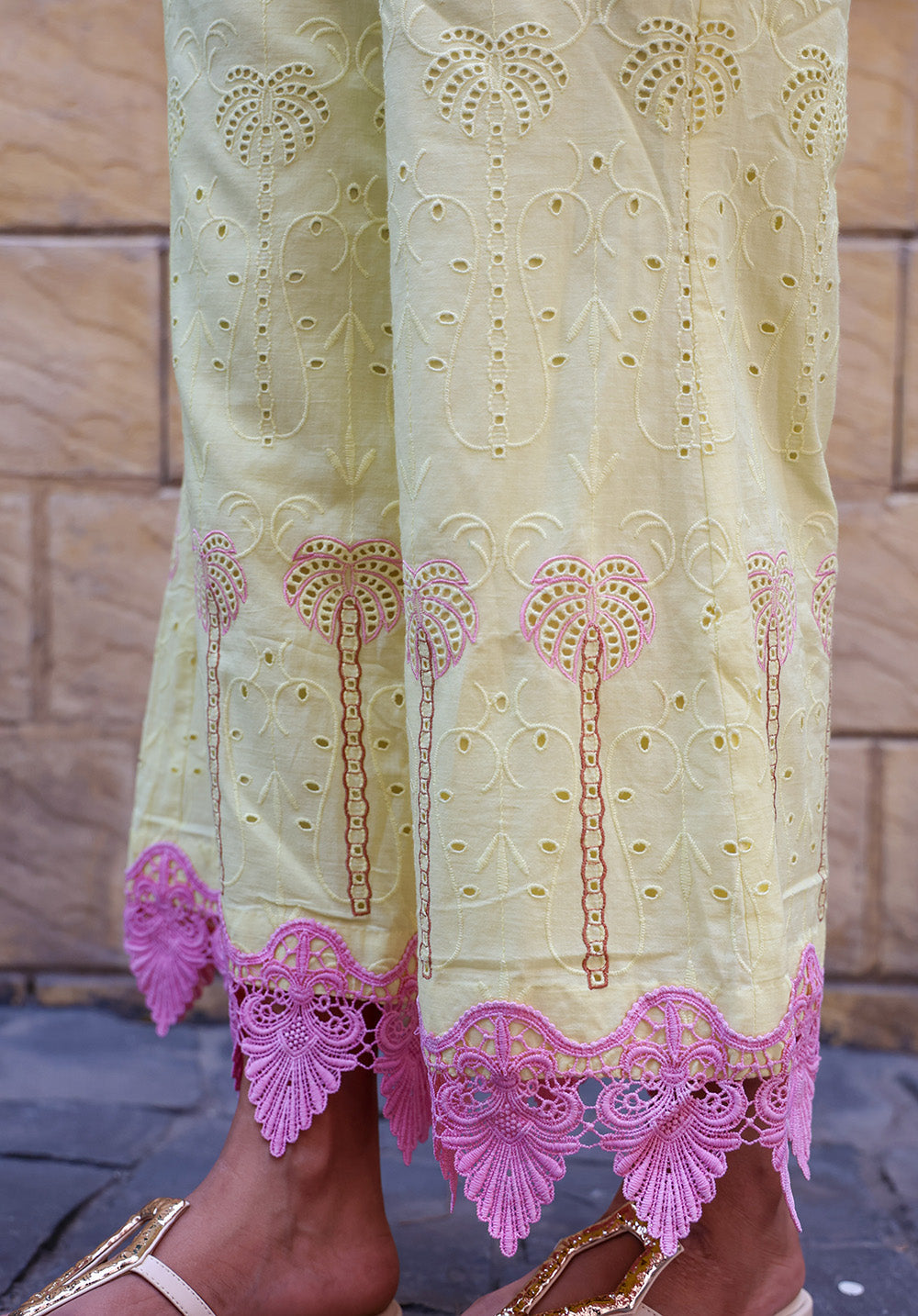 Detailed close-up of pink lace hem and palm embroidery on pastel yellow pants