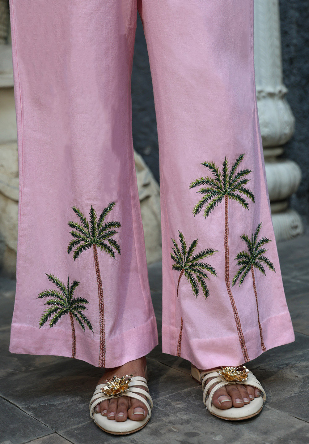 Close-up of blush pink wide-leg pants with palm tree embroidery detail near hem
urmish-ss26-palm-top-closeup